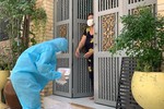 Tình nguyện viên mặc đồ bảo hộ đi tặng cơm từng nhà - Ảnh: T.N