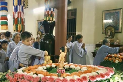 Em thơ được phụ huynh ẳm trên tay để Tắm Phật trong niềm háo hức