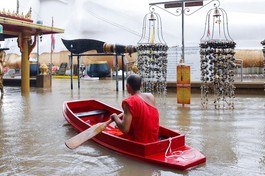 Nhà sư chèo thuyền cạnh một bức tượng Phật bị ngập trong nước lũ tại một ngôi chùa ở Ayutthaya, Thái Lan hôm 6-10