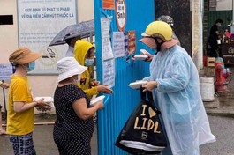 Tình nguyện viên tặng suất cơm chay đến thân nhân bệnh nhân tại cổng một bệnh viện - Ảnh: T.N