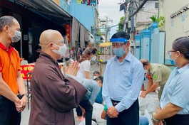 Thượng tọa Thích Trí Thông, Phó trụ trì chùa Viên Giác trao đổi với cán bộ khu cách ly để giúp đỡ người dân khó khăn - Ảnh: V.Gi