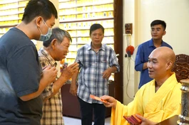 Đại đức Thích Giác Nghiêm, trụ trì chùa Phổ Minh trao tặng lì xì đến Phật tử và người dân về chùa đêm giao thừa - Ảnh: H.Ý/BGN