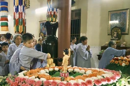 Em thơ được phụ huynh ẳm trên tay để Tắm Phật trong niềm háo hức
