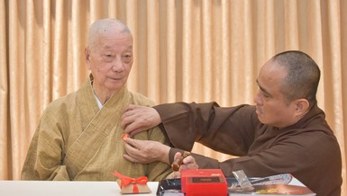 Thượng tọa Thích Tâm Hải, Tổng Biên tập Báo Giác Ngộ đương nhiệm đeo phù hiệu 50 năm Báo Giác Ngộ lên thông y của Đức Pháp chủ GHPGVN tại trụ sở tòa soạn chiều 30-12-2025 - Ảnh: Quảng Đạo