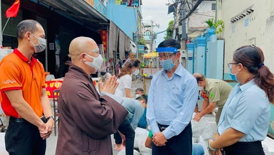 Thượng tọa Thích Trí Thông, Phó trụ trì chùa Viên Giác trao đổi với cán bộ khu cách ly để giúp đỡ người dân khó khăn - Ảnh: V.Gi