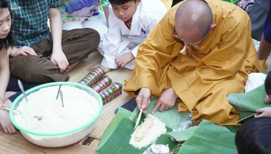 Đại đức Thích Thiện Hưng, trụ trì chùa Tam Bảo hướng dẫn gói bánh tét Tết cho các em thiếu nhi