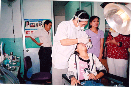 Bác sĩ Murase Takao đang khám răng cho một em thuộc nhóm trẻ em đường phố tại Hội Bảo trợ Bệnh