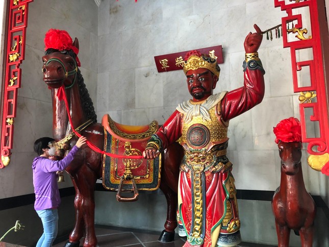 Một người Hoa nắm dây cương, rung lục lạc, vuốt thân ngựa Xích Thố và chui qua bụng nó để mong cầu may mắn tại &quot;chùa&quot; Ông (quận 5)