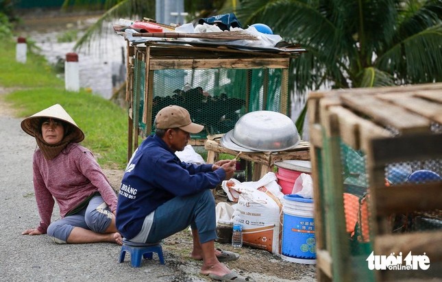 Người dân mệt mỏi di tản lên quốc lộ khi nhà còn ngập sâu trong lũ.