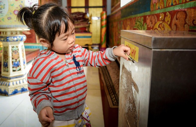 Các em cũng được cha mẹ chỉ dạy phát tâm cúng dường đến Tam bảo để được nhiều phước báu. Một em bé sau khi được mẹ hướng dẫn đang cố gắng để số tịnh tài vào thùng công đức
