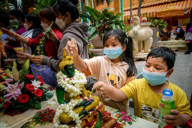 2 em bé đang thành kính tắm Phật để cầu nguyện Đức Phật gia hộ và che chở