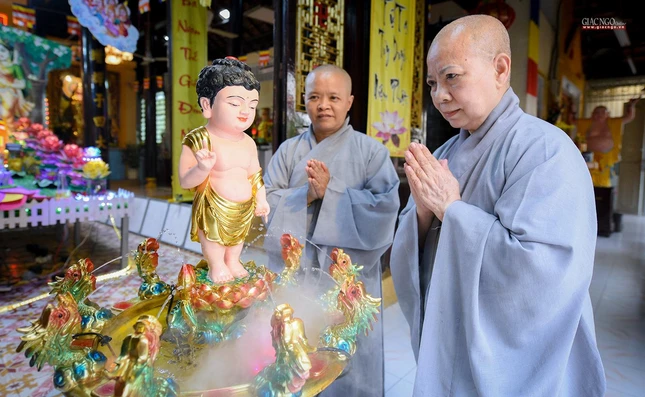 Sư cô Thích nữ Như Nghiêm và sư cô Thích nữ Diệu Trà thành kính chắp tay trang nghiêm trước tôn tượng Đức Phật đản sanh tại chùa Huệ Lâm