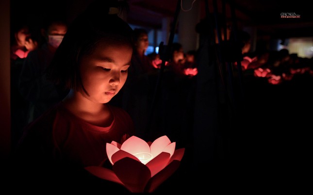 Một em bé được mẹ hướng dẫn thắp nến tưởng niệm