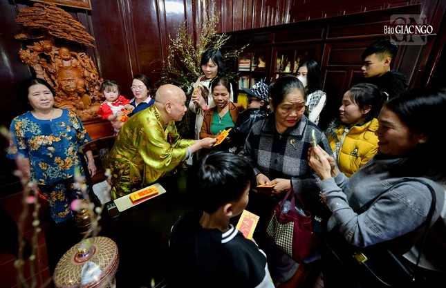 Sau khi lễ Phật, nhiều người đón nhận những món quà là phong bao lộc may mắn từ quý Thầy. Trong ảnh là Ôn Trí Tựu, trụ trì Quốc tự Thiên Mụ trao lộc đầu xuân đến một em nhỏ