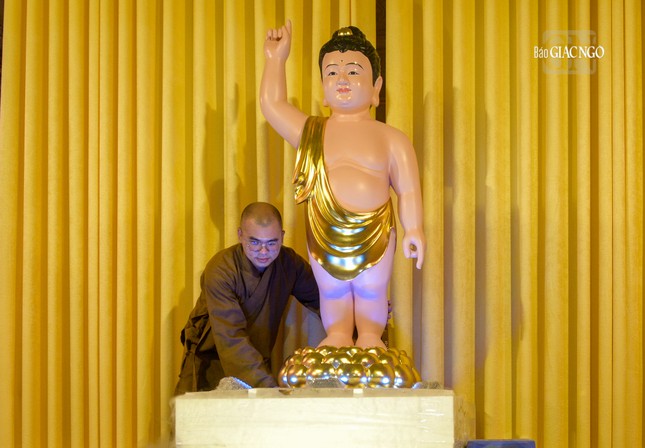 Trong ảnh là một vị tu sĩ đang điều chỉnh tôn tượng Đức Phật đản sinh tại lễ đài chùa Phước Duyên