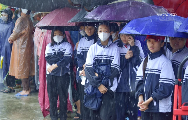 Các em học sinh đội mưa chờ nhận quà