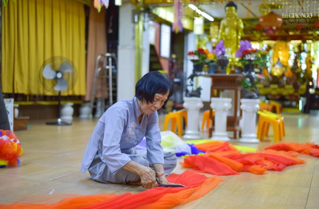 Lễ Tắm Phật của chùa Đức Quang sẽ diễn ra vào lúc 5 giờ chiều ngày 15-4 Âm lịch. Trong ảnh là Phật tử Diệu Mẫn (60 tuổi) đang cắt vải để kết thành hoa trang trí chùa