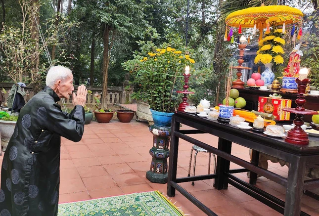 Một Phật tử lớn tuổi thực hiện nghi thức tâm linh trước khi dựng nêu