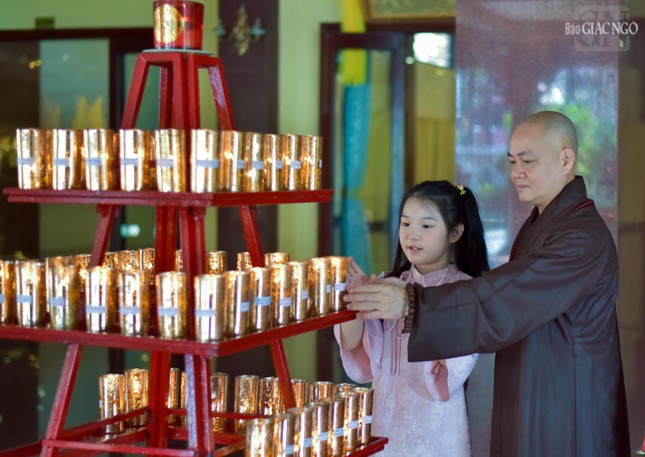 Các em nhỏ cũng được cha mẹ tạo điều kiện đến chùa, lễ Phật, gặp gỡ chư Tăng để được hướng dẫn làm các việc thiện lành đầu năm. Trong ảnh là Thượng tọa Thích Thiện Tạo đang hướng dẫn một Phật tử nhỏ đốt đèn cúng Phật, cầu bình an cũng như thắp sáng trí tuệ của mình