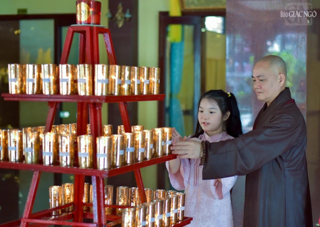 Các em nhỏ cũng được cha mẹ tạo điều kiện đến chùa, lễ Phật, gặp gỡ chư Tăng để được hướng dẫn làm các việc thiện lành đầu năm. Trong ảnh là Thượng tọa Thích Thiện Tạo đang hướng dẫn một Phật tử nhỏ đốt đèn cúng Phật, cầu bình an cũng như thắp sáng trí tuệ của mình