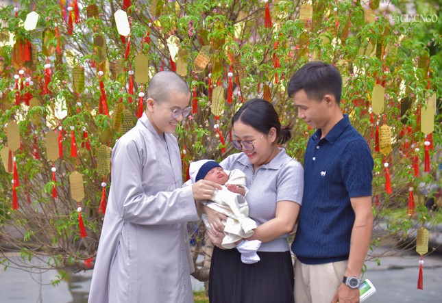 Trong ảnh là một gia đình nhỏ đang nhờ một Sư cô cầu nguyện bình an cho đứa con của mình