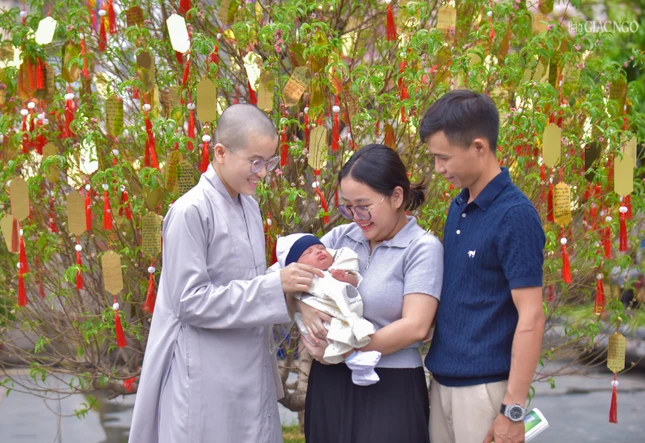 Trong ảnh là một gia đình nhỏ đang nhờ một Sư cô cầu nguyện bình an cho đứa con của mình