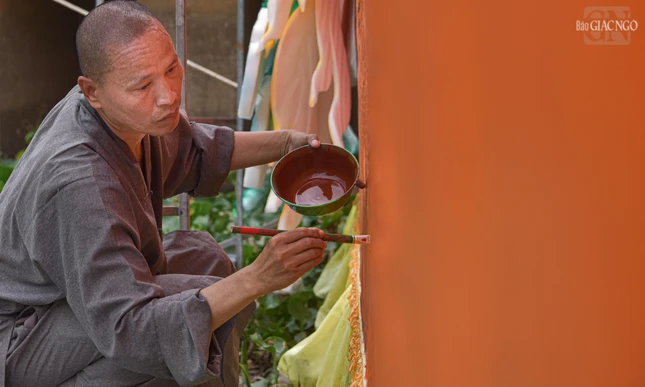 Thượng tọa Thích Minh Quang đang chăm chú vẽ phác thảo những đường nét trên thân con rồng bên mạn thuyền