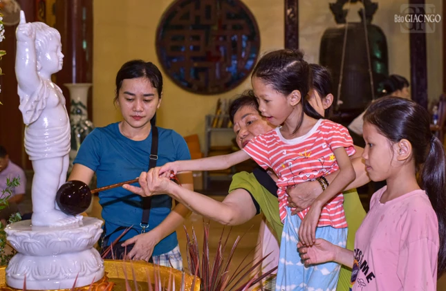 Một em nhỏ được mẹ hướng dẫn thực hiện nghi thức Mộc dục