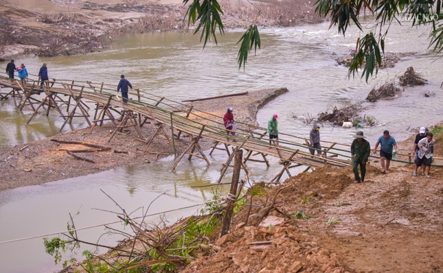 Người dân băng qua cầu làm tạm để nhận quà sau khi cầu Trung Thắng bị lũ làm sập