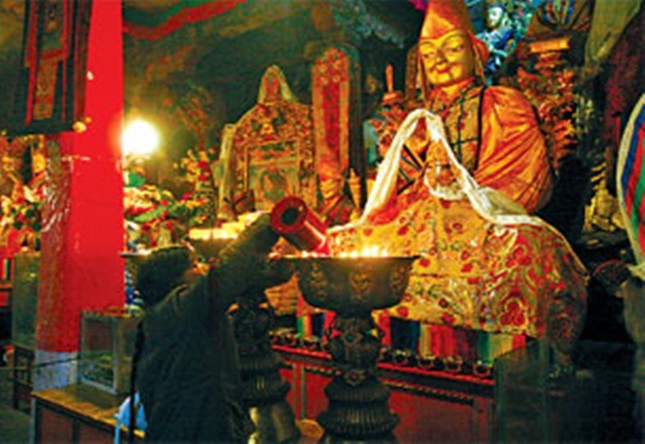 Những người hành hương châm bơ trâu Yak trước tượng Đức Phật