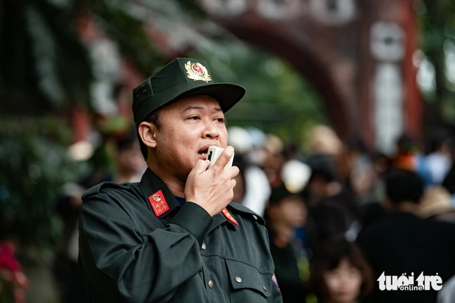 Lực lượng chức năng liên tục phát loa thông báo cho người dân, du khách xếp hàng theo quy định, phòng chống mất cắp - Ảnh:Nam Trần