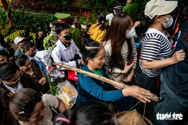 Một người phụ nữ với gánh đồ lễ giữa dòng người lên trên phía đền Hạ - Ảnh: Nam Trần