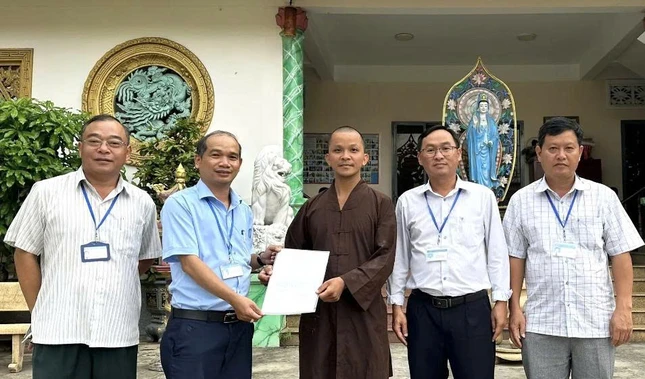 Đại đức Thích Thiện Lâm, trụ trì chùa Linh Sơn đón nhận giấy phép sửa chữa chùa từ chính quyền xã Bà Điểm