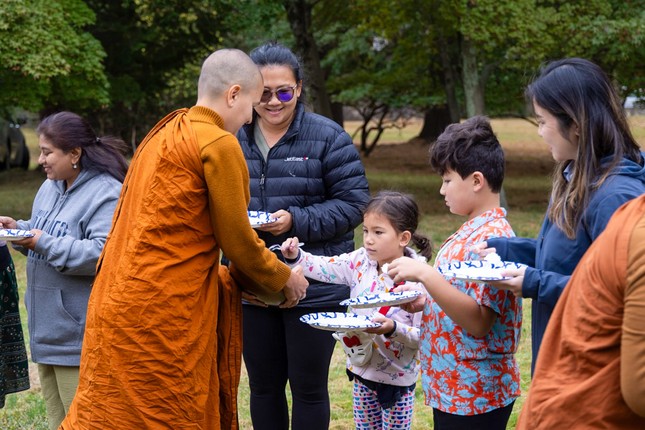 Các em nhỏ theo sự hướng dẫn của cha mẹ thành tâm dâng phẩm vật lên chư Tăng Ni Các em nhỏ theo sự hướng dẫn của cha mẹ thành tâm dâng phẩm vật lên chư Tăng Ni