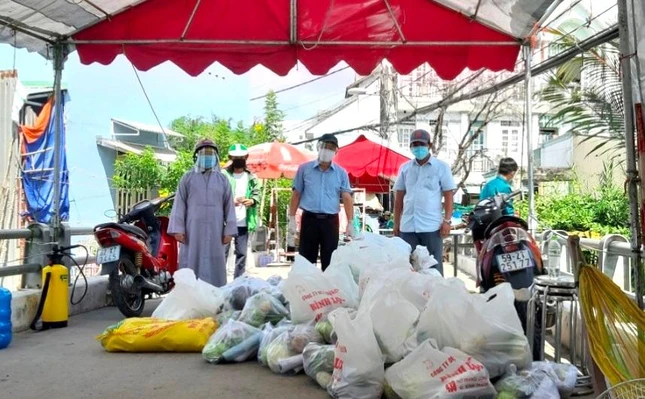 Sư cô TN Lệ Nhân, chùa Pháp Võ; ông Nguyễn Văn Hưng, Chủ tịch UBMTTQ xã Phú Xuân; Phật tử Minh Hạnh, Phó Giám đốc Trung tâm Mồ côi Pháp Võ trao quà tại khu phong tỏa - Ảnh: CTV