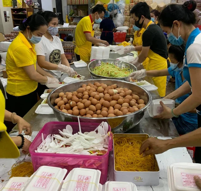 Tình nguyện viên chuẩn bị cho cơm vào hộp tại bếp ăn chùa Tường Nguyên