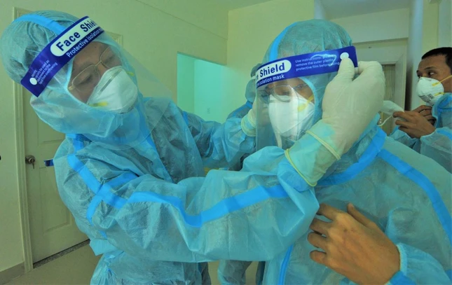 Bác sĩ Phạm Đăng Trọng Tường, Giám đốc Bệnh viện Dã chiến thu dung số 12 giúp đỡ tác giả chỉnh đồ bảo hộ - Ảnh: Tuổi Trẻ