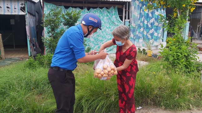Thành viên Đội tình nguyện xã Phú Thuận B trao bánh mì chay