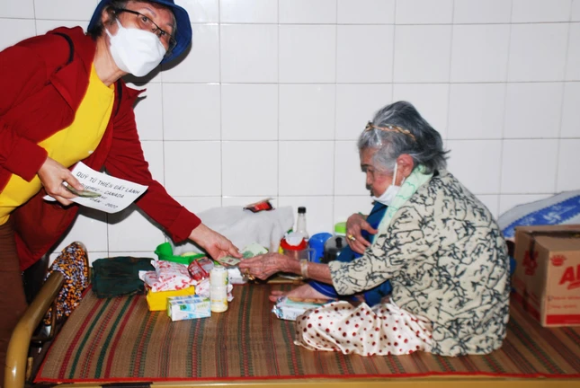 Thành viên đoàn trao quà đến người già neo đơn