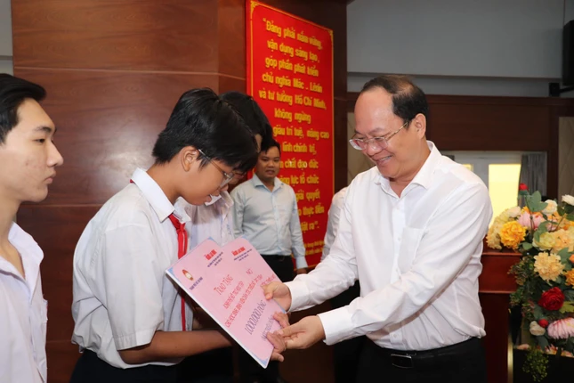 Phó Bí thư Thành ủy TP.HCM Nguyễn Hồ Hải trao hỗ trợ kinh phí học tập đến các em học sinh - Ảnh: MTTP