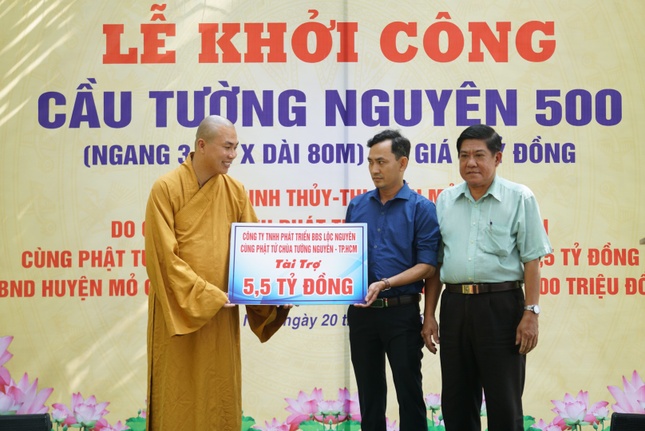 Đại đức Thích Minh Phú đại diện đơn vị tài trợ trao bảng ủng hộ kinh phí xây cầu - Ảnh: TN