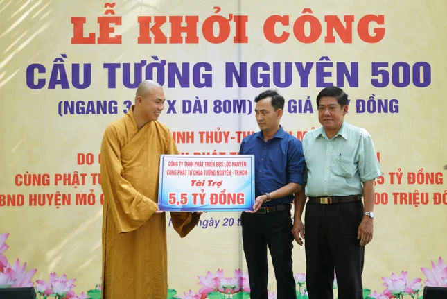 Đại đức Thích Minh Phú đại diện đơn vị tài trợ trao bảng ủng hộ kinh phí xây cầu - Ảnh: TN