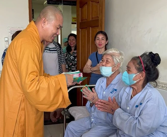 Đại đức Thích Minh Phú trao lộc chúc mừng bệnh nhân sau phẫu thuật - Ảnh: TN