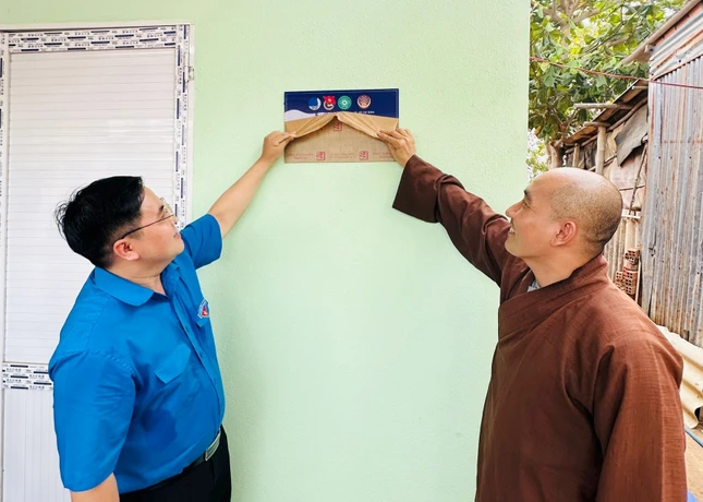 Đại đức Thích Thiện Nghĩa và ông Phan Thanh Trẻ tháo bảng lưu niệm, khánh thành nhà mới - Ảnh: H.N