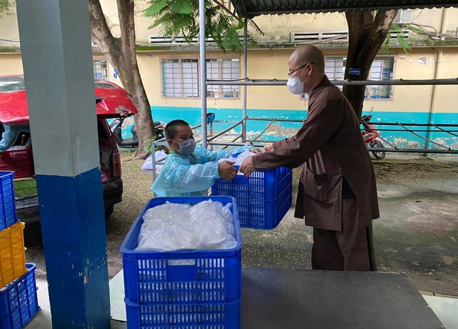 Đại đức Thích Minh Đạo, trụ trì chùa Nam Thiên Nhất Trụ trao các suất cơm đến các tình nguyện viên vận chuyện về khu cách ly