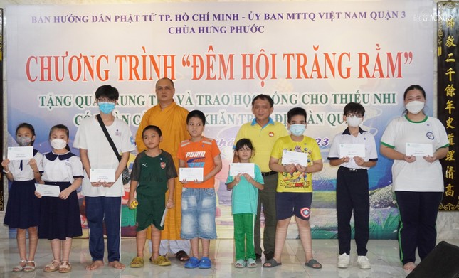 Thượng tọa Thích Thiện Chơn cùng ông Nguyễn Ngọc Châu - Phó Chủ tịch Thường trực Ủy ban MTTQVN Q.3 trao các suất học bổng đến các em