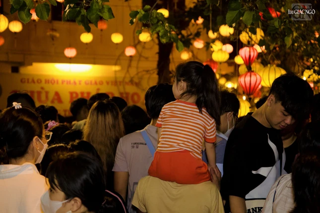 Em bé được cõng trên lưng người thân dự lễ