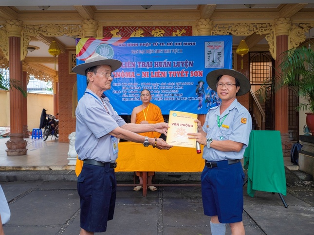 Huynh trưởng cấp Tín Nguyên Hàm-Võ Quốc Đạo, Phó Thư ký, Chánh Văn phòng Phân ban Gia đình Phật tử TP.HCM trao quyết định thành lập Ban quản trại Liên trại đến Huynh trưởng cấp Tấn Minh Hạnh - Huỳnh Văn Long, Phó Phân ban Gia đình Phật tử TP.HCM, Trại trưởng Liên trại huấn luyện