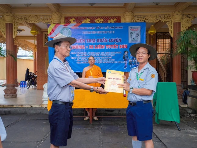 Huynh trưởng cấp Tín Nguyên Hàm-Võ Quốc Đạo, Phó Thư ký, Chánh Văn phòng Phân ban Gia đình Phật tử TP.HCM trao quyết định thành lập Ban quản trại Liên trại đến Huynh trưởng cấp Tấn Minh Hạnh - Huỳnh Văn Long, Phó Phân ban Gia đình Phật tử TP.HCM, Trại trưởng Liên trại huấn luyện