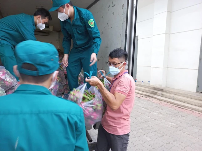 Tình nguyện viên Đinh Anh Hoàng Vũ (áo hồng) khuân vác thực phẩm do mạnh thường quân tiếp sức đến bệnh viện dã chiến